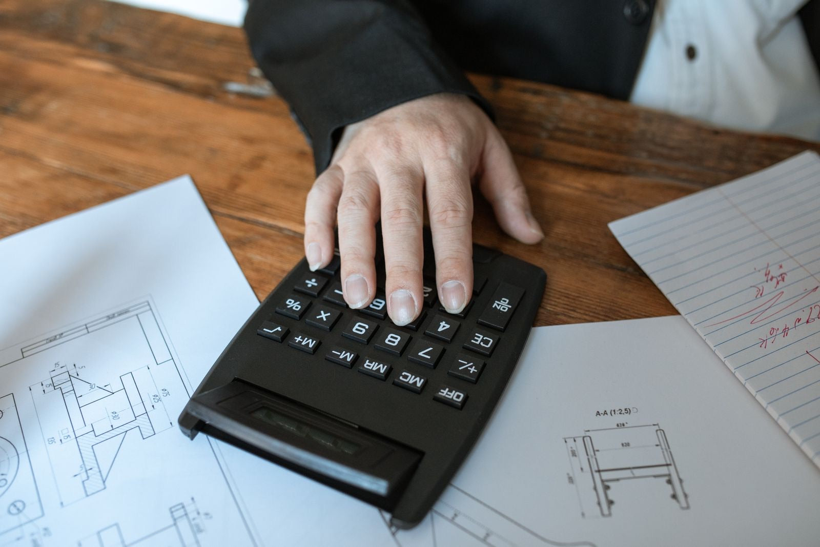 Calculating LEED certification cost with a calculator on architectural blueprints