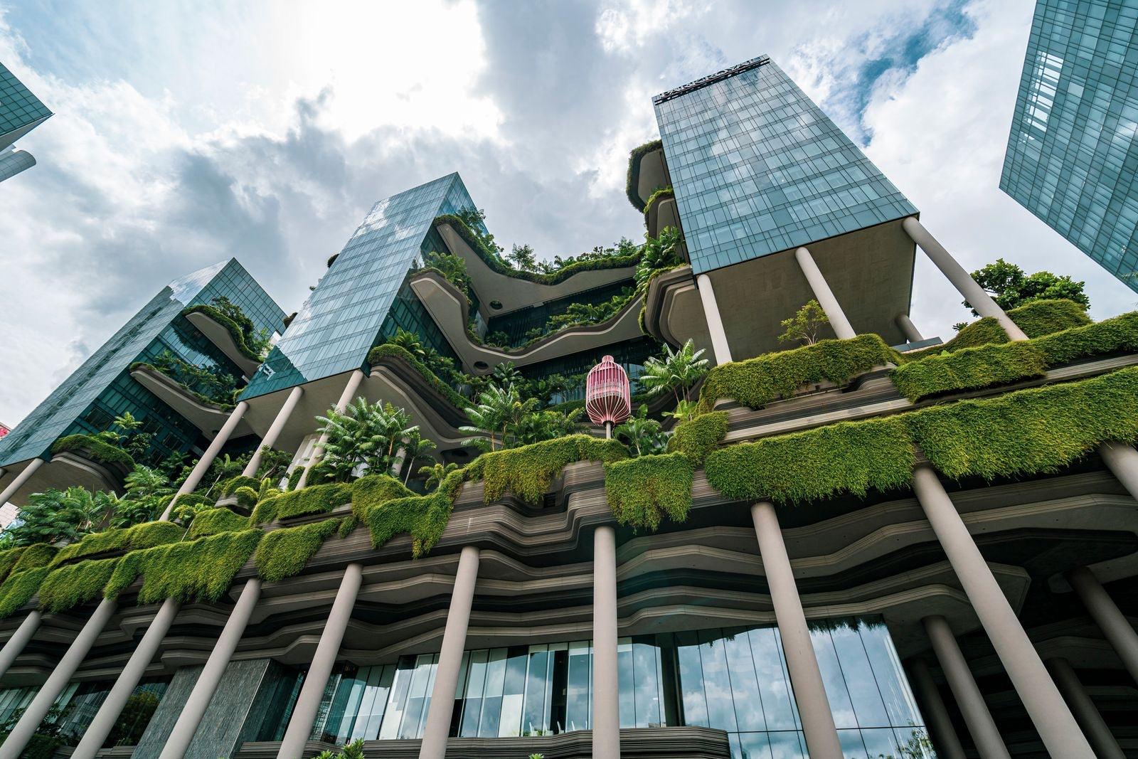 Modern green building with lush planted terraces under a bright daytime sky